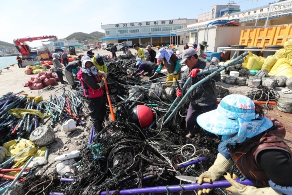 ▲ 지난 4월께 제주 추자도 해안변에 밀려 온 엄청난 양의 해양쓰레기를 수거하는 모습. ©Newsjeju