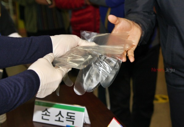 ▲ 발열 증상이 없는 유권자는 손을 소독한 뒤 비치된 위생장갑을 착용하고 투표사무원에게 신분증을 제시하면 된다. ©Newsjeju