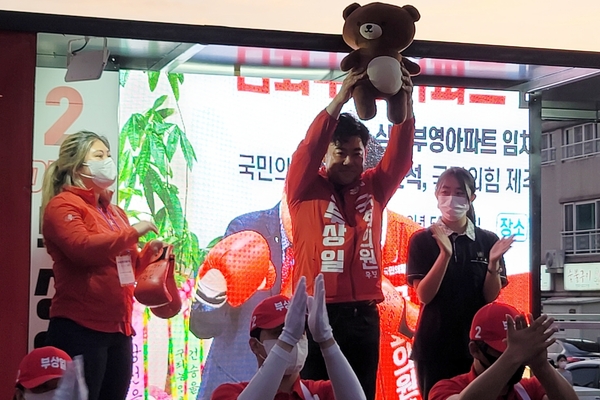 ▲ 부상일 국회의원 후보는 자신의 마스코트가 된 '미련 곰탱이'에 맞는 곰 인형을 선물로 받고 치켜들었다. ©Newsjeju